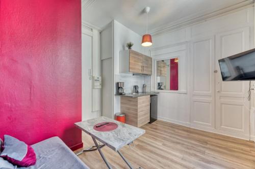 un salon avec un mur rose et une table dans l'établissement Le Red Touch votre F2 au cœur de Rouen !, à Rouen