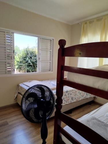 a bedroom with a fan on the floor and a window at Flor de Jabuticabeira in Jaguariúna