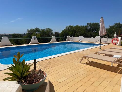 a swimming pool with two chairs and an umbrella at Self-contained floor of Quinta / Villa in Guia