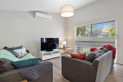 a living room with two couches and a flat screen tv at Jetty Road Holidays - 33 Jetty Road in Normanville