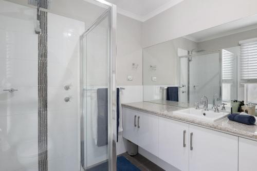 Un baño blanco con ducha y lavabo. en Jetty Road Holidays - 33 Jetty Road, en Normanville