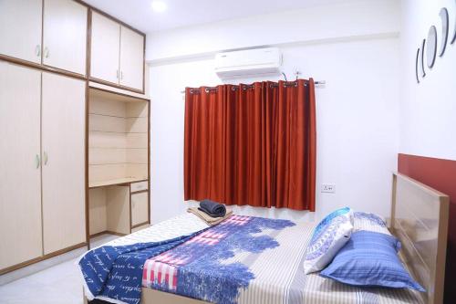 a bedroom with a bed and a red curtain at Royal Residency 3BHK, Near Rameshwaram cafe, HiTech City in Hyderabad