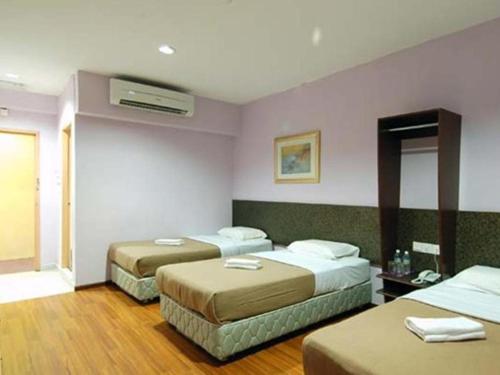 a hotel room with two beds and a mirror at Aristo Hotel @ Putatan in Pekan Putatan