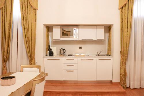 a small kitchen with white cabinets and a table at Al Bailo Di Venezia in Venice