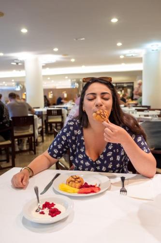 サ・コマにあるWelikehotel Marfil Playaのテーブルに座って食事を食べている女性