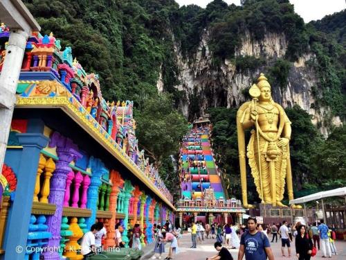 un groupe de personnes marchant dans une rue avec une statue dans l'établissement ARK HOTEL BATU CAVES, à Batu Caves