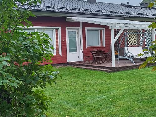 a red house with a deck with a table and chairs at Ervastinkallio in Kalajoki