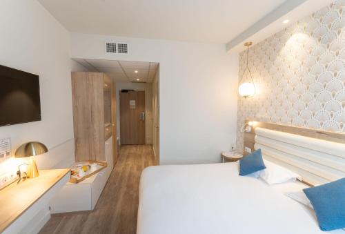a bedroom with a white bed and a tv at Brit Hotel Ker Lann Aeroport - Parc Expo in Bruz