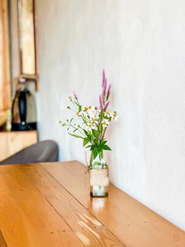 a vase of flowers sitting on a wooden table at Pu Luong Jungle Lodge in Pu Luong