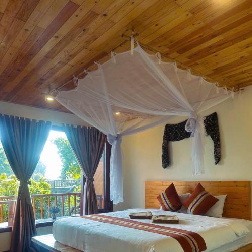 a bedroom with a canopy bed with a balcony at Pu Luong Jungle Lodge in Pu Luong