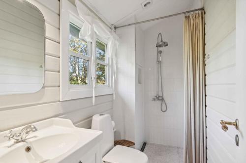 a white bathroom with a sink and a toilet at Lovely Summer House In North Zealand in Vejby
