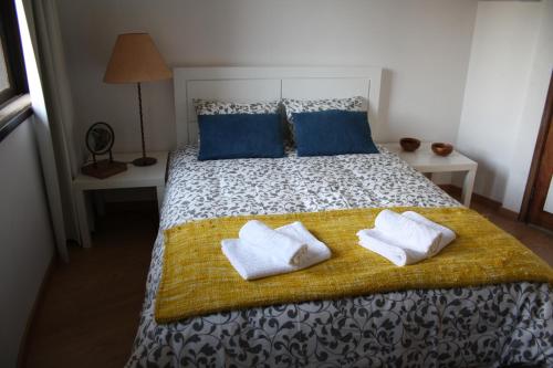 a bed with a white blanket and pillows on top of it at Alegria Rooms in Porto