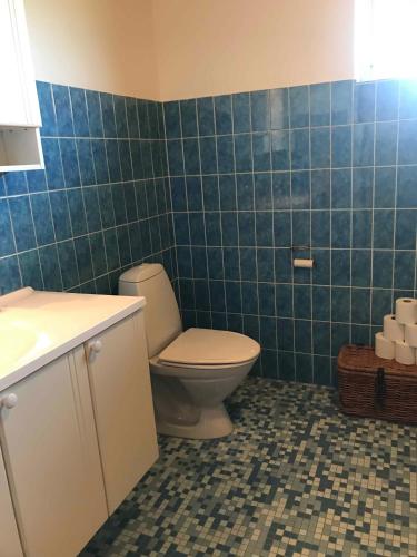 a bathroom with a toilet and a blue tiled wall at Lovely Holiday Home On Lolland in Errindlev
