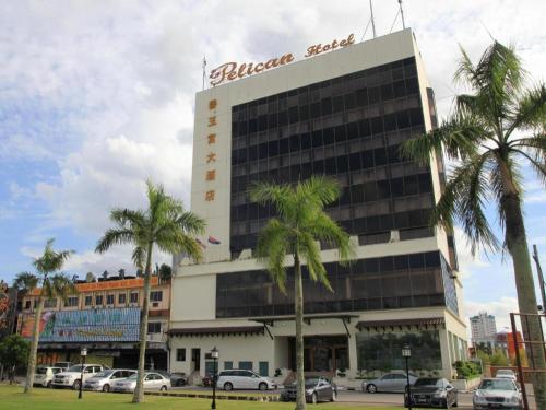 a hotel with palm trees in front of a building at Pelican Hotel in Batu Pahat