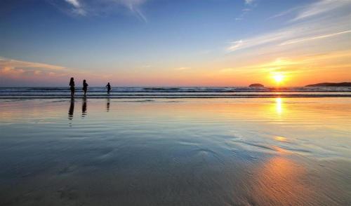 two people standing on the beach watching the sunset at Eminent Hotel in Kota Kinabalu