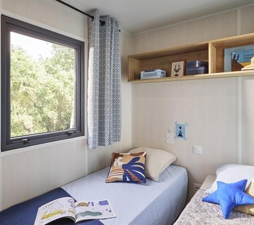 une petite chambre avec deux lits et une fenêtre dans l'établissement Camping l'Oso, à Porto-Vecchio