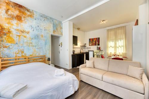 une chambre avec un lit blanc et un canapé dans l'établissement Jean Studio Aitre Saint-Maclou, à Rouen