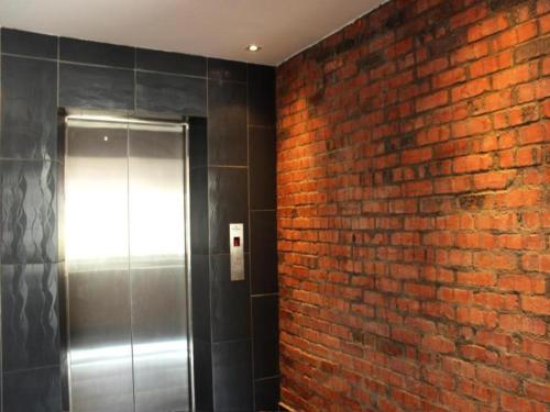a bathroom with a brick wall and a metal elevator at Rock & Roll Hotel Klang in Klang