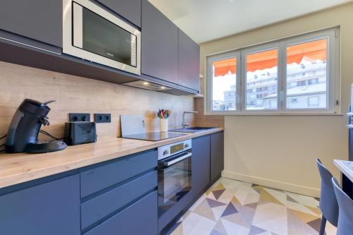 - une cuisine avec des placards bleus et un four micro-ondes dans l'établissement Victoria magnifique appartement spa vue cathédrale, à Rouen