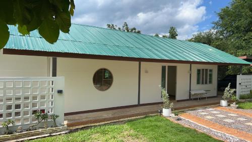 a small white house with a green roof at Siam Butterfly Farm in Ban Huai Salok