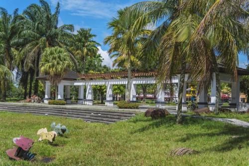 S Avenue Hotel في جوهور باهرو: حديقة فيها نخيل ومبنى