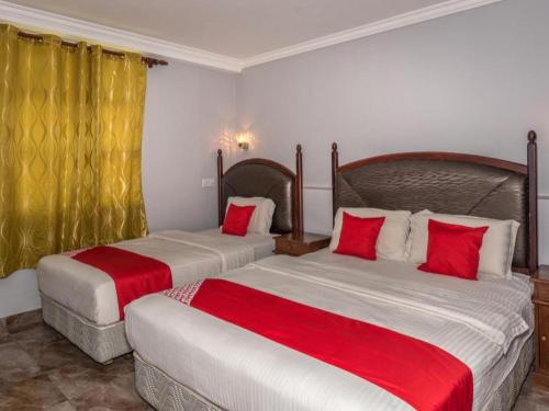 two beds in a hotel room with red pillows at OYO 890 Hotel RK Cahaya in Labuan
