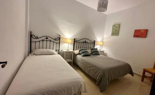 a bedroom with two beds and two tables and two lamps at Casa a 65 metros de la Playa in El Palmar