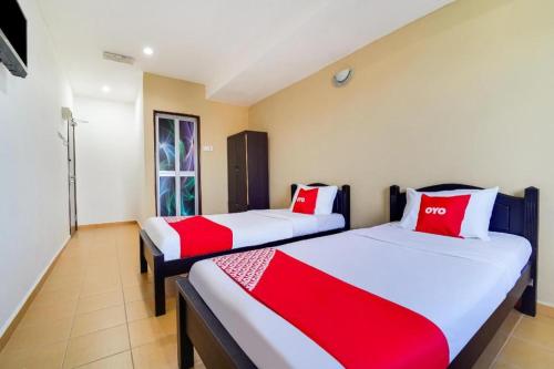 two beds in a room with red and white pillows at OYO 44058 MOTEL SRE BAYAM in Lunas