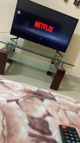 ein Fernseher auf einem Glastisch neben einer Fernbedienung in der Unterkunft Hyderabad bungalow in Hyderabad