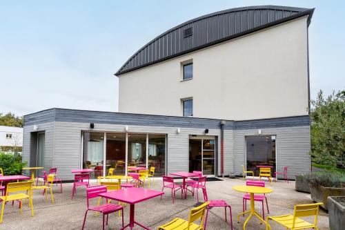 a group of tables and chairs in front of a building at ibis Styles Prévessin Genève Aéroport in Prévessin