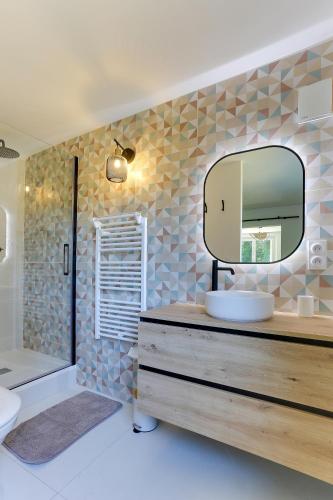 une salle de bain avec un lavabo et un miroir dans l'établissement Merlin - charmant apt avec jardin, à Bruz