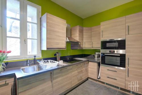 une grande cuisine avec des placards en bois et un évier dans l'établissement Appartement familial 2 chambres, 2 salles de bains, à Tours