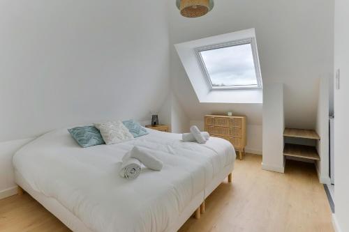 une chambre avec un grand lit blanc avec une fenêtre dans l'établissement Morgane - appt avec jardin partagé, à Bruz
