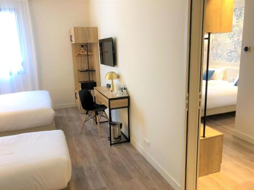 a room with a bed and a desk with a mirror at Brit Hotel Ker Lann Aeroport - Parc Expo in Bruz