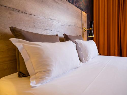 a bed with white pillows and a wooden headboard at Brit Hotel Ker Lann Aeroport - Parc Expo in Bruz
