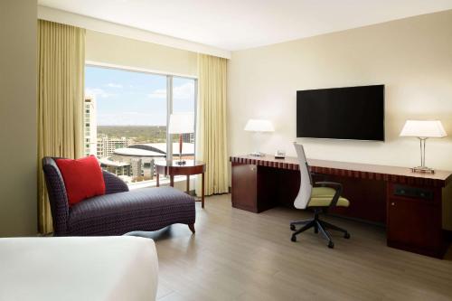 a hotel room with a desk and a chair and a television at Hilton Charlotte Uptown in Charlotte