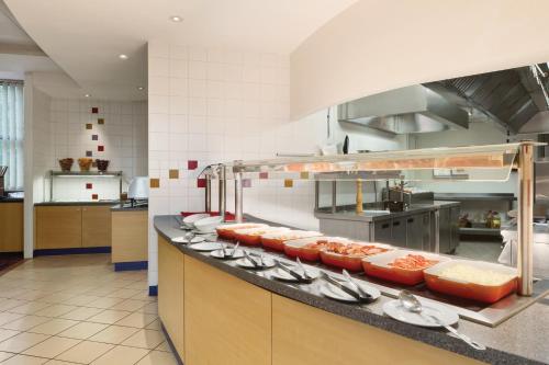 a kitchen with a counter with plates and utensils at Ramada London North in Barnet