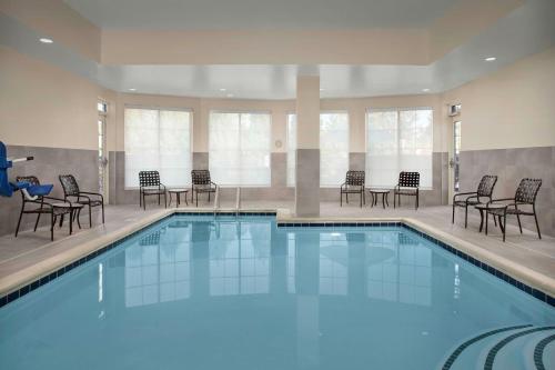 a large swimming pool with chairs and tables at Hilton Garden Inn Fredericksburg in Fredericksburg