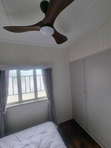 a ceiling fan in a bedroom with a bed and a window at Queensland Charm in Maryborough in Maryborough