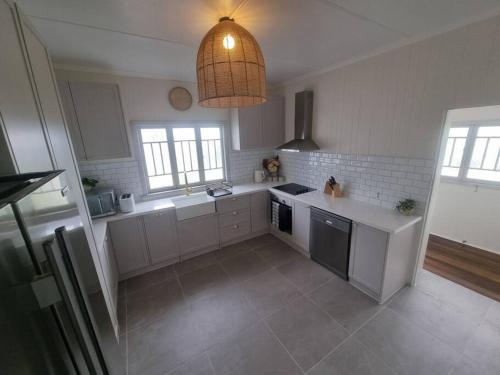 a kitchen with white appliances and a pendant light at Queensland Charm in Maryborough in Maryborough