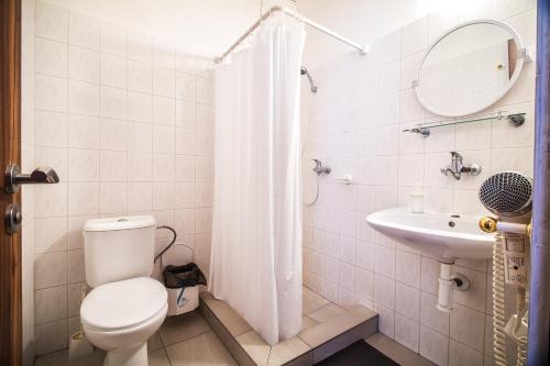 a white bathroom with a toilet and a sink at Hotel Skála in Malá Skála