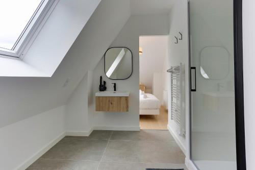 une salle de bain blanche avec un lavabo et un miroir dans l'établissement Viviane - appt avec jardin partagé, à Bruz
