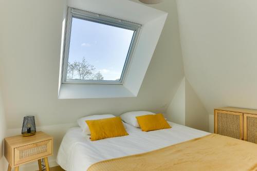 une chambre avec un lit avec des oreillers jaunes et une fenêtre dans l'établissement Viviane - appt avec jardin partagé, à Bruz