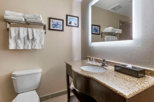 a bathroom with a toilet and a sink with a mirror at Comfort Suites Phoenix Airport in Tempe