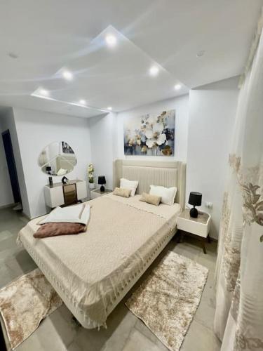 a white bedroom with a large bed and a mirror at Attrayant et unique in Mahdia