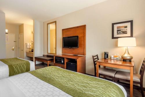 a hotel room with two beds and a desk with a television at Comfort Inn Ellsworth - Bar Harbor in Ellsworth