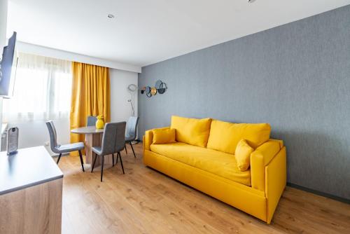 a living room with a yellow couch and a table at Brit Hotel Ker Lann Aeroport - Parc Expo in Bruz