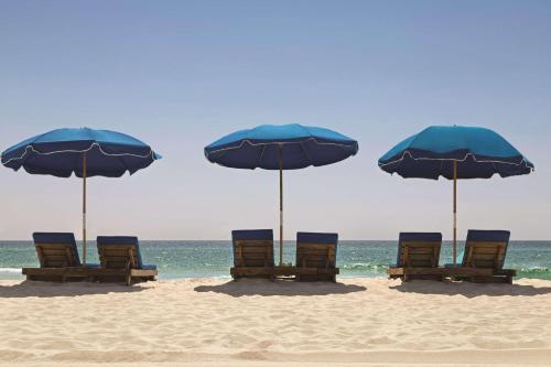 a group of chairs and umbrellas on a beach at Radisson Beachfront Hotel - Panama City Beach in Panama City Beach