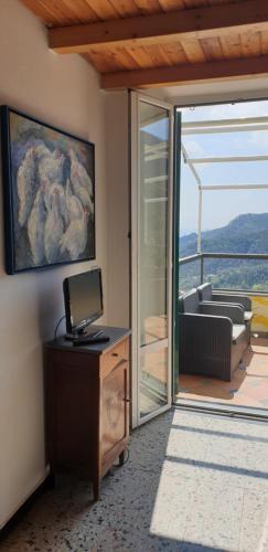a room with a television and a sliding glass door at Agriturismo OlivArancio in Leivi