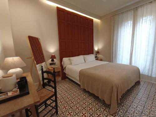 a bedroom with a bed and a table and a chair at Uma Suites Parada del Marqués in Seville